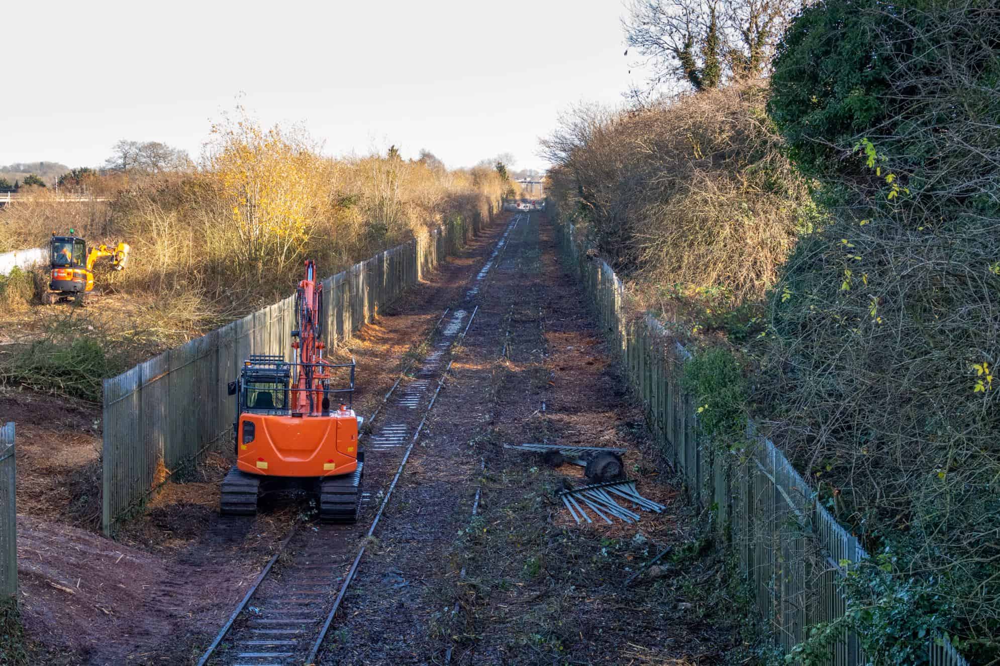 Branch line after vegetation clearance, with an excavator working on the track